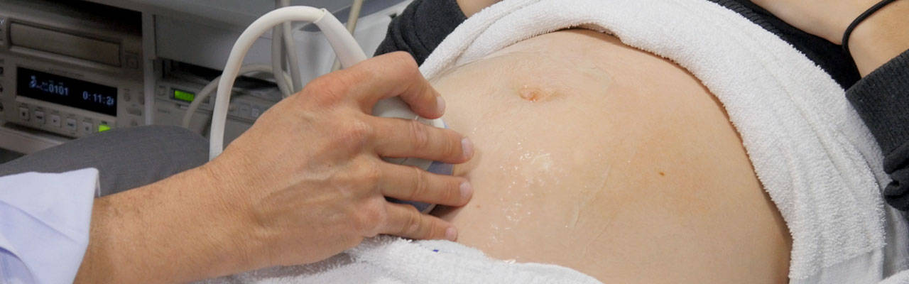 a hand performing an Ultrasound on a pregnant woman